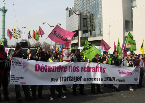 The banner of "Solidaires," a grouping of several labor unions, reads: "To defend our retirement plans is to share the wealth by taxing profits," and, on the left side, "To share the wealth is to raise wages and the minimum wage."